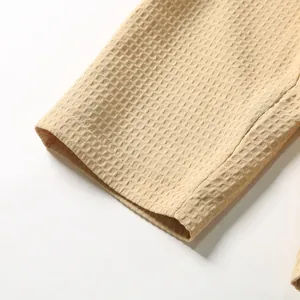 Detailaufnahme der beige Waffelstrick-Stoffstruktur an einem lässigen Herrenblazer.