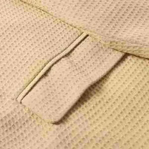 Detailgetreue Nahaufnahme des beigen Waffelstrickstoffs an der Tasche eines Herrenblazers.