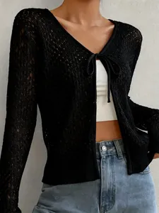 Dettaglio ravvicinato di un cardigan nero in maglia traforata con chiusura a laccetto sul davanti.