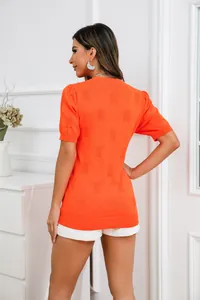 Gedetailleerd achteraanzicht van oranje gebreide top met pofmouwen en textuurpatroon