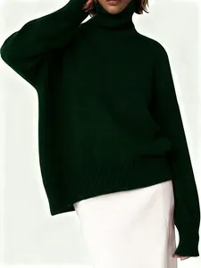 Detalle de un acogedor jersey de punto de cuello alto oversize verde oscuro con puños de canalé