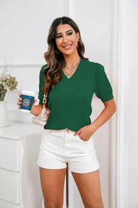 Model draagt een groene gebreide top met V-hals en een witte short in een studio