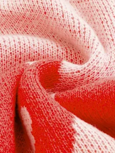 Macro detail of soft red and white knitted sweater fabric showing high quality texture