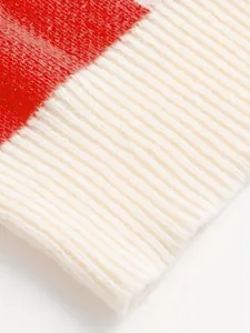 Detailed view of the ribbed cuff and knit texture on a red and white cardigan.