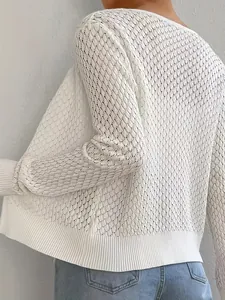 Dettaglio della complessa trama a maglia traforata sulla maglia bianca a maniche lunghe.