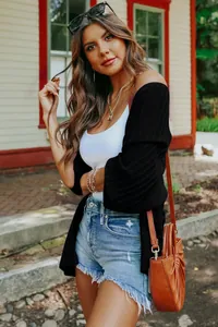 Detailed view of women's lightweight black ribbed knit cardigan styled with denim shorts.