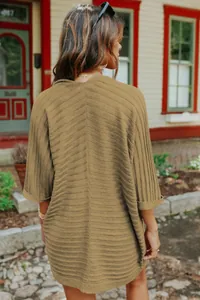 Back view of a khaki ribbed knit cardigan with half sleeves in a cozy outdoor setting.