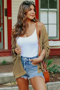 Detail view of a stylish khaki five-point sleeve knit cardigan worn with denim shorts