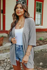 Lifestyle shot of a stylish women's grey ribbed knit cardigan with five-point sleeves