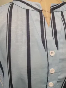 Close-up of light blue striped blouse with white buttons and linen-like texture