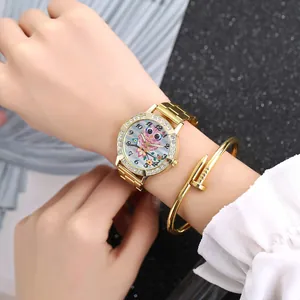 Women's gold quartz watch with rhinestone bezel and owl dial paired with a nail bracelet