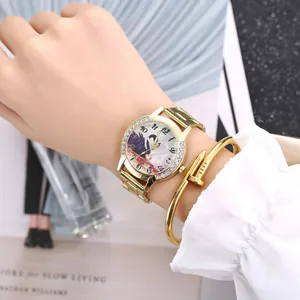 Close-up detail of women's gold quartz watch with rhinestones and nail-shaped bracelet