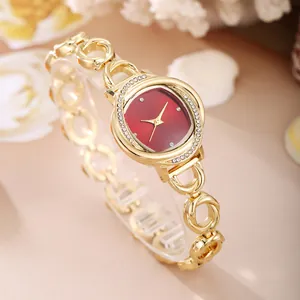 Detail view of elegant gold-tone bracelet watch with red dial and rhinestone bezel