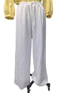 Détail du pantalon large en coton et lin blanc présentant une finition gaufrée chic.