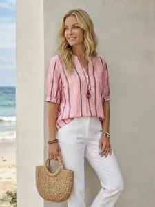 Detailed summer beach shot of woman wearing a pink striped v-neck short sleeve blouse