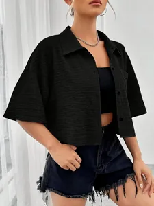 Detailed view of black textured cropped shirt with buttons and short sleeves