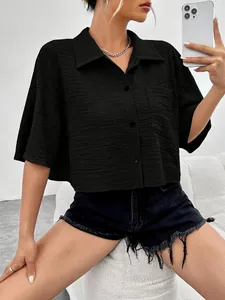 Close-up of a stylish black textured cropped shirt with buttons and a chest pocket.