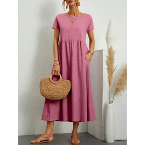 Full length view of a pink casual short sleeve maxi dress paired with a woven straw bag.