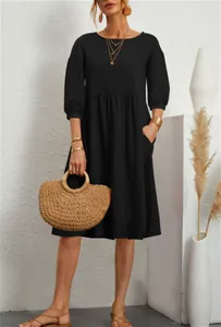 Detail view of a black cotton linen midi dress with lantern sleeves and side pockets.