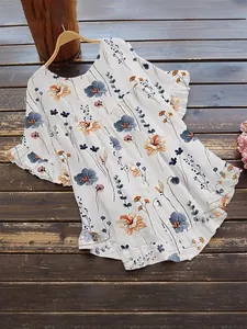 Détail du chemisier blanc à imprimé fleuri avec manches à volants et boutons en bois.