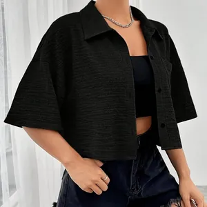 Detail view of black textured women's cropped shirt with buttons and front pocket