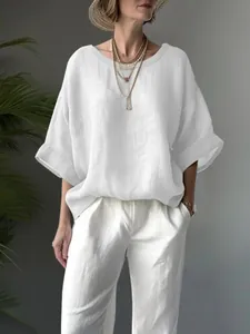 Detail view of a loose white linen-look blouse on a model for a casual summer style.