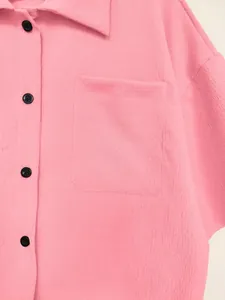 Detailed view of the textured fabric and front pocket on this pink button-down shirt.