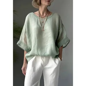 Close-up of loose-fitting green linen-textured shirt with a relaxed round neckline