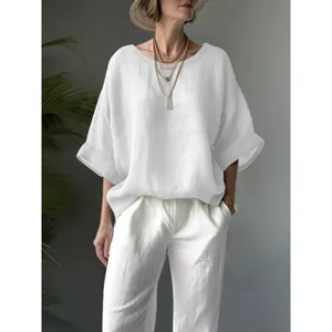 Detail shot of a comfortable white loose-fit linen blouse with a round neck and drop shoulder