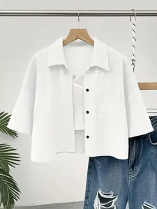 Detail view of white textured cropped short-sleeved shirt with contrast buttons