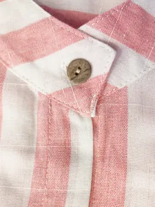 Vue rapprochée d'un col de chemise en lin à rayures roses avec bouton en bois rustique.