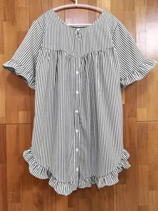 Vue détaillée d'une blouse rayée ample avec ourlet à volants sur un fond de mur en bois