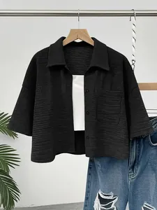 Close-up detail of black textured cropped shirt with button-down front and front pocket