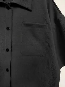 Close-up detail of textured fabric on black button-down shirt with front pocket