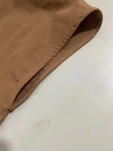 Macro view of side pocket detail and reinforced stitching on a brown cotton linen dress