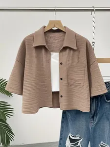 Close-up detail of textured brown short-sleeved button-up shirt with front pocket detail