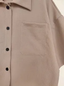 Macro view of khaki textured fabric on a women's short-sleeve button-up shirt with pocket.