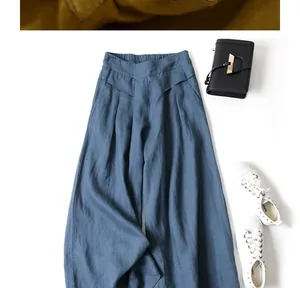 Flat lay detail of blue cotton linen wide-leg pants with stylish black bag and sneakers.