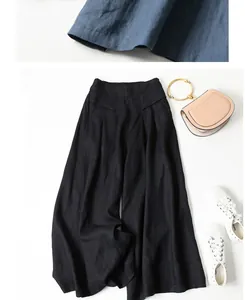 Detail view of black cotton linen wide-leg pants styled with a handbag and sneakers.
