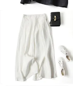 High-waisted white cotton linen wide-leg pants styled with black bag and white sneakers.