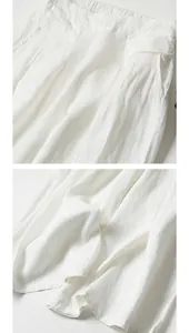 Detailed view of white cotton-linen wide-leg pants showing waist and fabric texture.