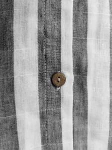 Gros plan du tissu d'une chemise à rayures grises et blanches avec bouton en bois.
