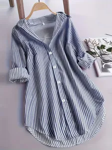Close-up of a blue and white striped oversized shirt on a wooden hanger with magazine props
