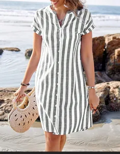 Woman wearing a grey and white striped summer shirt dress on a sunny beach