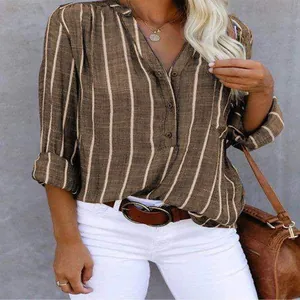 Detailed view of women's brown vertical striped V-neck blouse paired with white pants