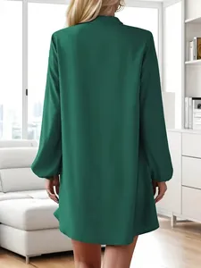 Back view of a dark green long-sleeved A-line shirt dress in a modern home setting