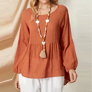Detail of a loose terracotta cotton-linen babydoll top featuring elegant lantern sleeves.