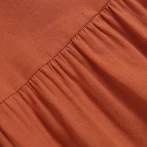 Detailed close-up showing the pleated orange fabric of a summer cotton linen shirt