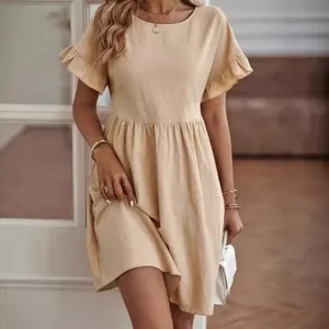 Detail view of a loose-fitting beige cotton linen dress with round neck and ruffled sleeves.