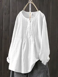 Detail of white cotton linen long sleeve pleated blouse with round neck for women